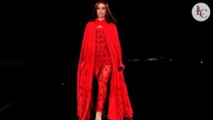 Modelo desfila look vermelho impactante com capa longa durante o Le Défilé da L’Oréal Paris na Paris Fashion Week 2025, reforçando o poder da cor como manifesto visual.